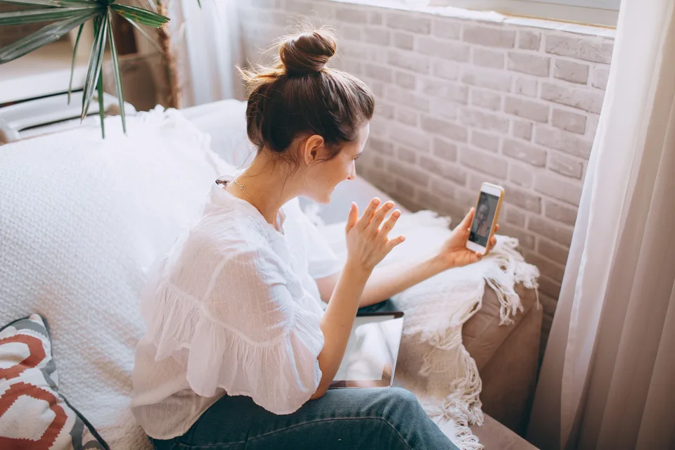 Woman using her smartphone at home to connect with remote care